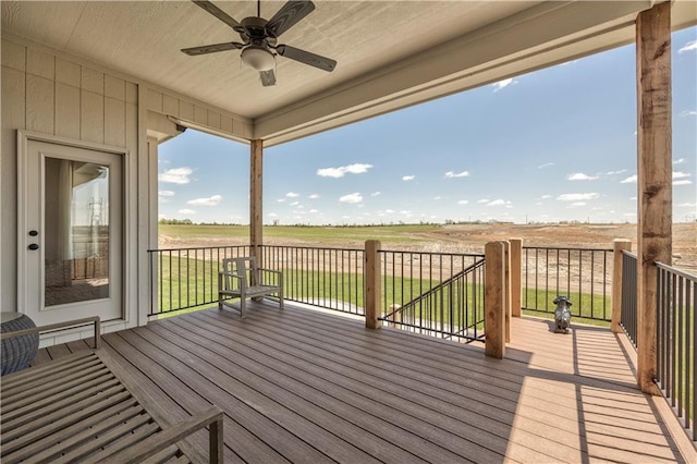 wooden deck with ceiling fan, a lawn, and a rural view