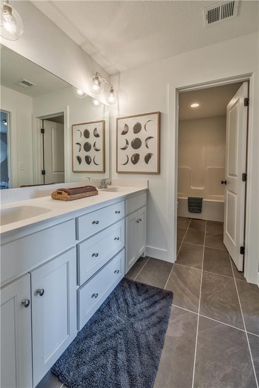 full bathroom with double vanity, visible vents, a sink, and tile patterned floors