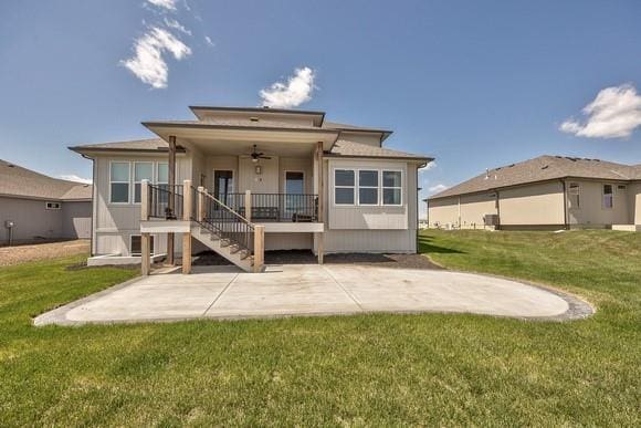 rear view of property with a ceiling fan, a patio area, a lawn, and stairs