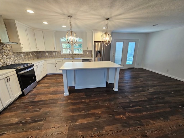 kitchen featuring hanging light fixtures, a kitchen island, dark hardwood / wood-style flooring, white cabinets, and appliances with stainless steel finishes