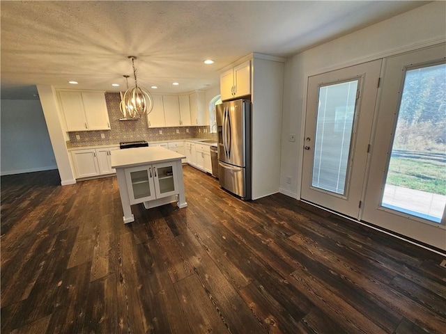 kitchen with a kitchen island, tasteful backsplash, pendant lighting, white cabinets, and appliances with stainless steel finishes