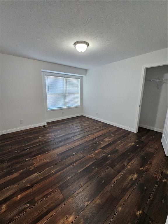 spare room with a textured ceiling and dark hardwood / wood-style flooring