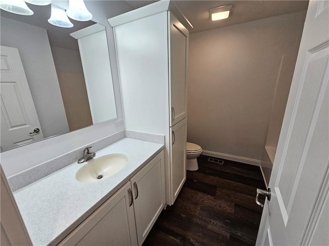 bathroom with a tub to relax in, vanity, hardwood / wood-style flooring, and toilet