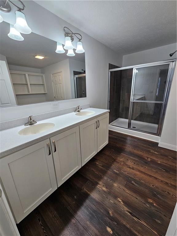 bathroom featuring a textured ceiling, vanity, hardwood / wood-style flooring, and a shower with shower door