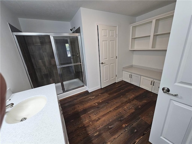 bathroom with hardwood / wood-style flooring, vanity, a shower with shower door, and a textured ceiling