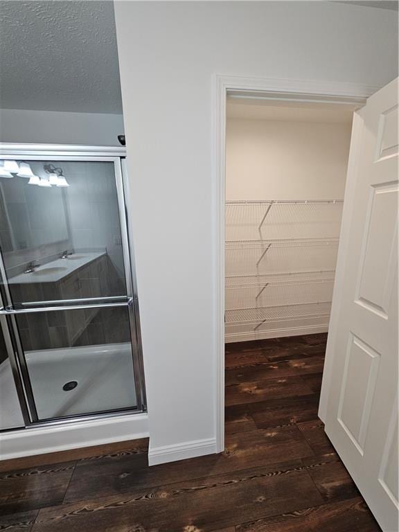 bathroom featuring wood-type flooring, a textured ceiling, and walk in shower