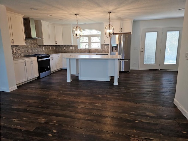 kitchen featuring a center island, wall chimney range hood, dark hardwood / wood-style floors, pendant lighting, and appliances with stainless steel finishes