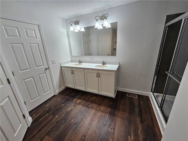 bathroom with a chandelier, hardwood / wood-style floors, vanity, and a shower with shower door