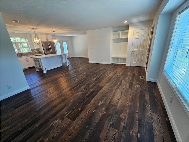 unfurnished living room featuring dark wood-type flooring and an inviting chandelier