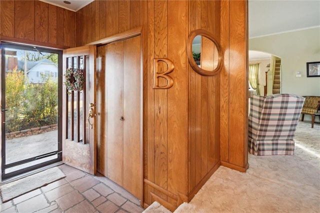 carpeted entryway featuring wooden walls