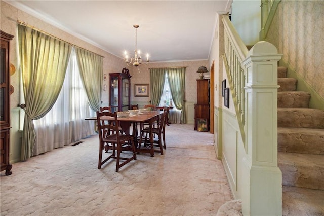 carpeted dining room featuring a notable chandelier, plenty of natural light, and ornamental molding