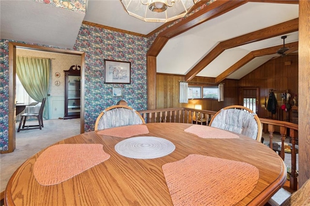 dining area with vaulted ceiling with beams, wood walls, carpet floors, and ceiling fan