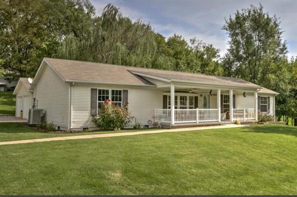 single story home with a garage, covered porch, and a front yard