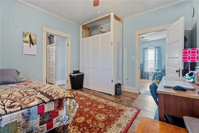 bedroom with ceiling fan, wood-type flooring, wood walls, and ornamental molding