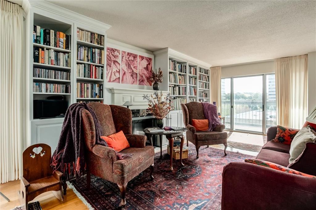 living area with built in shelves, light hardwood / wood-style floors, and a textured ceiling