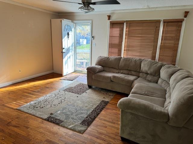 living room featuring ceiling fan, ornamental molding, a textured ceiling, and hardwood / wood-style flooring