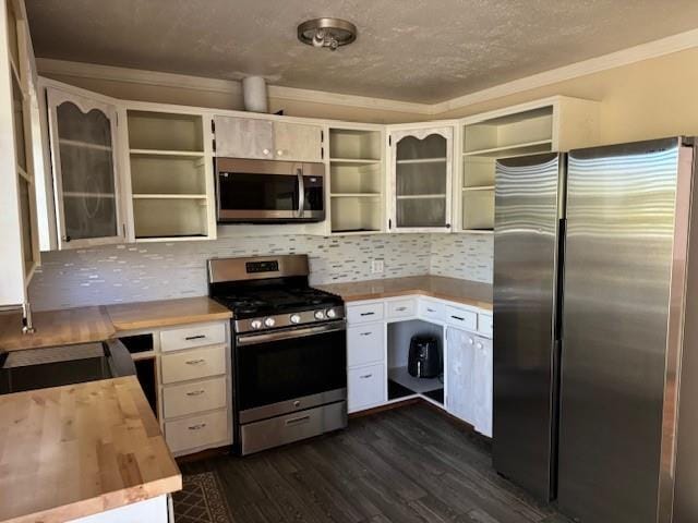 kitchen with crown molding, dark hardwood / wood-style flooring, stainless steel appliances, and tasteful backsplash