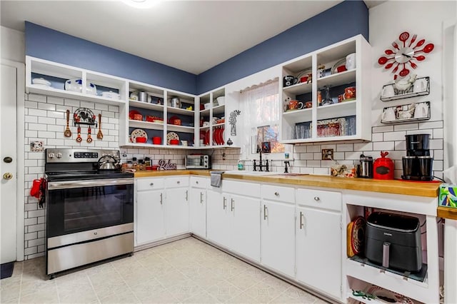 kitchen featuring backsplash, white cabinetry, stainless steel range with electric cooktop, and wooden counters