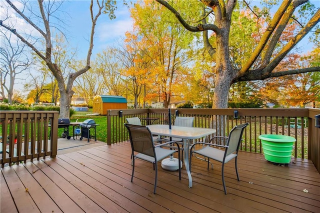 wooden deck featuring a lawn, a grill, and a storage unit