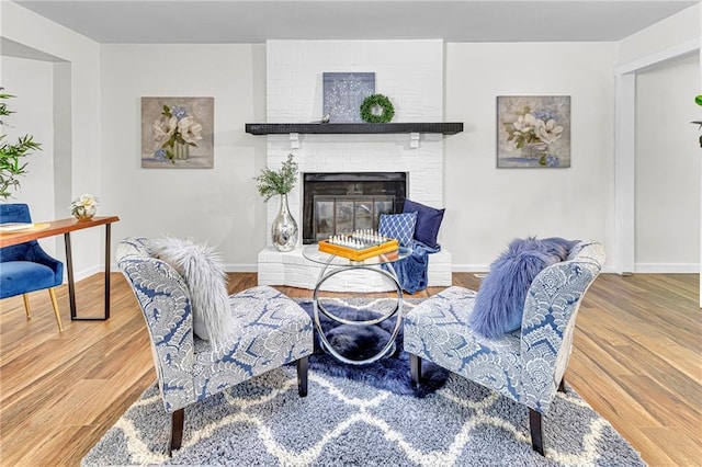 living area with wood-type flooring and a brick fireplace