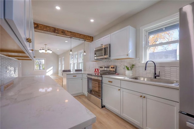 kitchen featuring white cabinetry, sink, hanging light fixtures, and appliances with stainless steel finishes