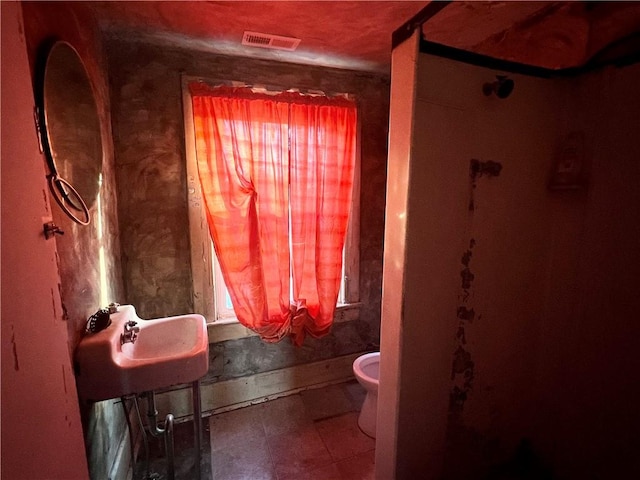 bathroom with toilet, plenty of natural light, and sink