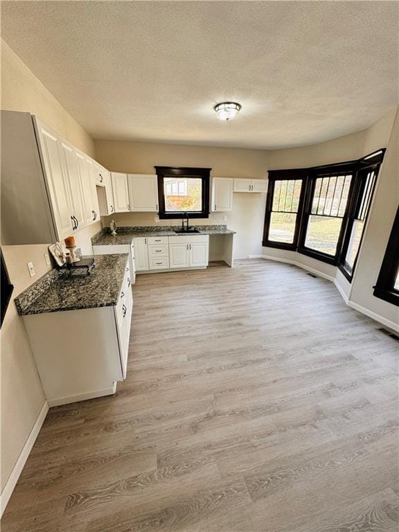 1610 S Olive St, Pittsburg, KS 66762 - kitchen featuring light wood-type flooring, a textured ceiling, white cabinets, and dark stone counters
