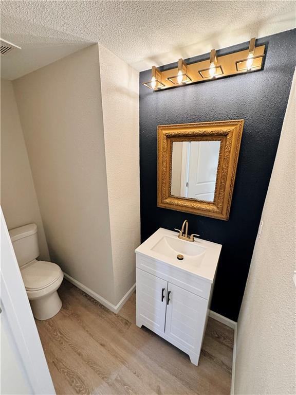 1610 S Olive St, Pittsburg, KS 66762 - bathroom with wood finished floors, vanity, and a textured ceiling