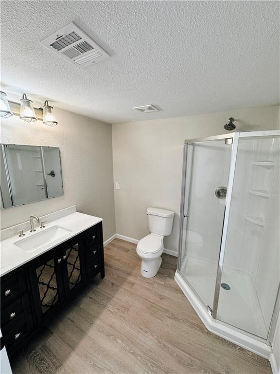 1610 S Olive St, Pittsburg, KS 66762 - bathroom featuring wood finished floors, a shower stall, vanity, and a textured ceiling