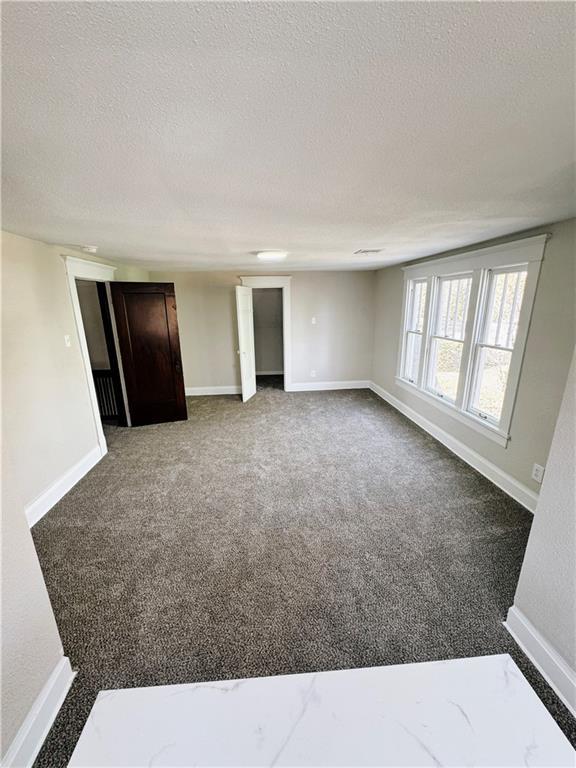 1610 S Olive St, Pittsburg, KS 66762 - carpeted empty room with a textured ceiling and baseboards