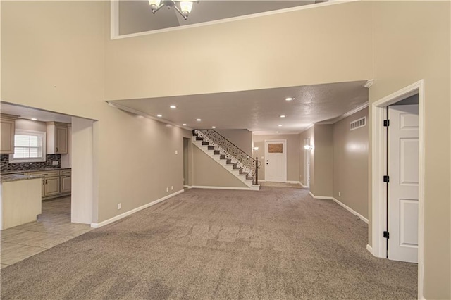 unfurnished living room featuring light carpet, a high ceiling, and ornamental molding