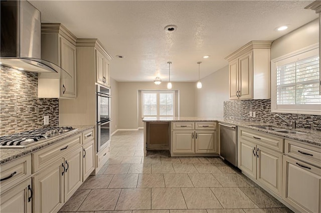 kitchen featuring hanging light fixtures, wall chimney exhaust hood, appliances with stainless steel finishes, tasteful backsplash, and kitchen peninsula