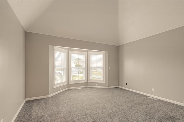 carpeted empty room with lofted ceiling