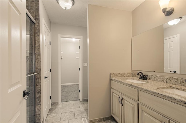 bathroom featuring vanity, a shower with shower door, and a textured ceiling