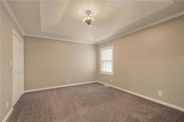 carpeted empty room with a raised ceiling and ornamental molding