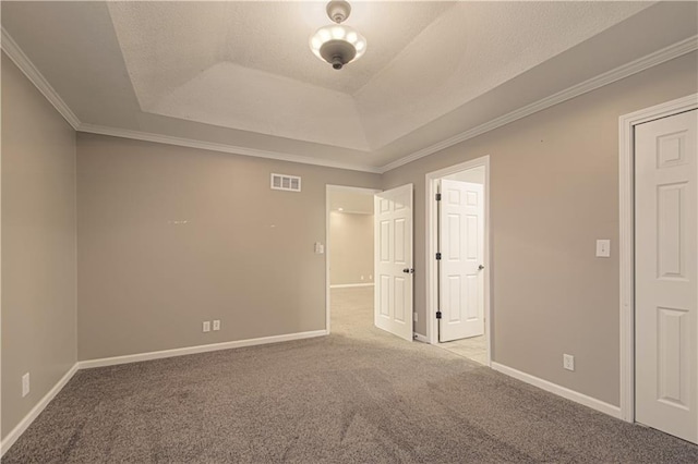 spare room with ornamental molding, light carpet, and a tray ceiling