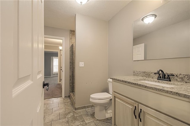 bathroom featuring vanity, toilet, a shower with shower door, and a textured ceiling