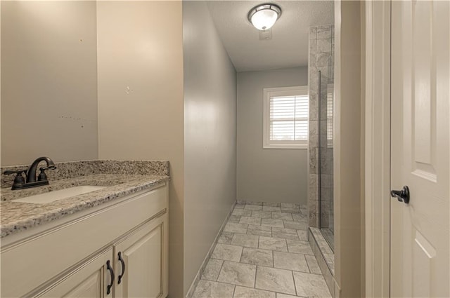 bathroom with a textured ceiling, vanity, and walk in shower