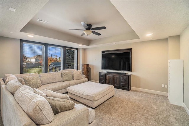 living room featuring ceiling fan, a raised ceiling, and light carpet