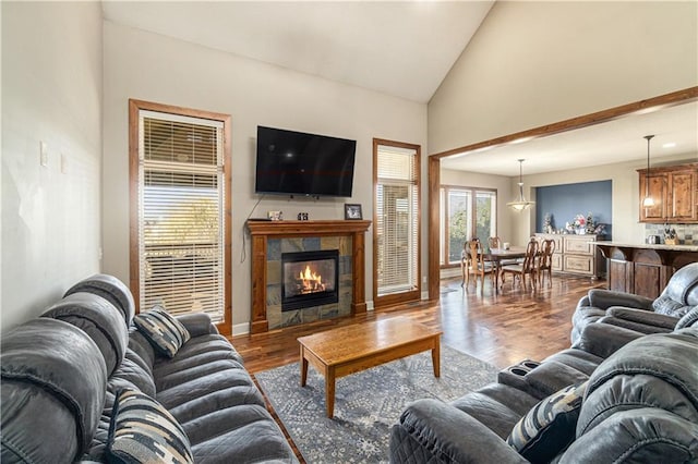 living room featuring dark hardwood / wood-style flooring, high vaulted ceiling, and a tile fireplace