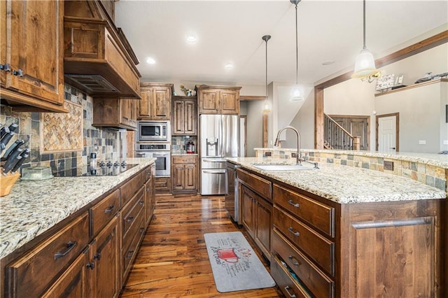 kitchen featuring sink, backsplash, hanging light fixtures, stainless steel appliances, and a spacious island