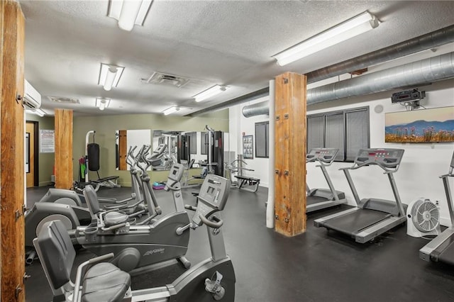 workout area with a textured ceiling and a wall mounted AC