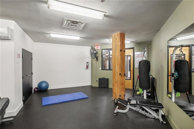 workout area featuring a textured ceiling and a wall unit AC