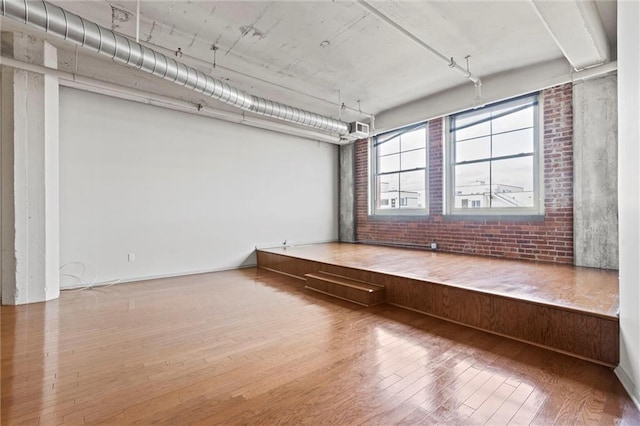 spare room with wood-type flooring and brick wall