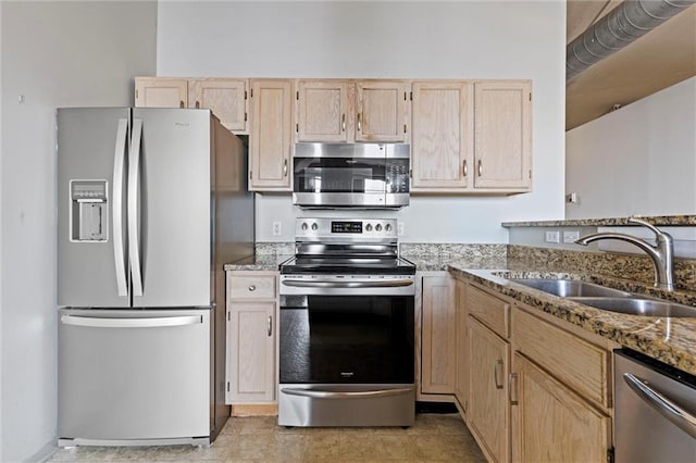 kitchen with light stone countertops, light brown cabinetry, stainless steel appliances, and sink