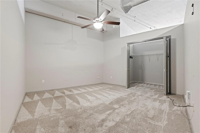 unfurnished bedroom featuring a towering ceiling, a closet, light colored carpet, and ceiling fan