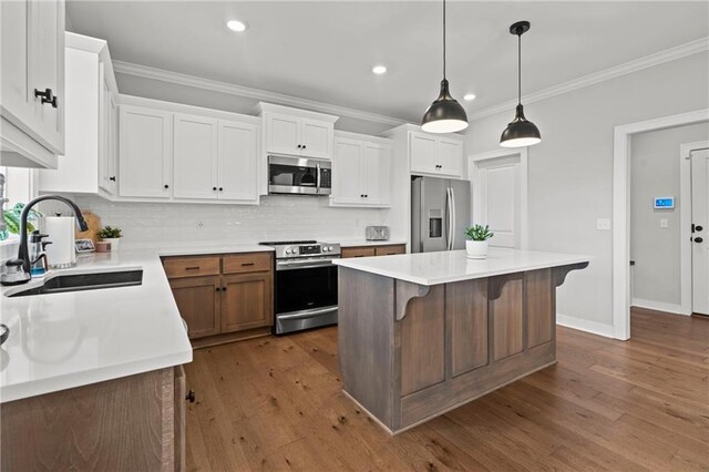 kitchen featuring appliances with stainless steel finishes, sink, white cabinets, a kitchen breakfast bar, and a center island