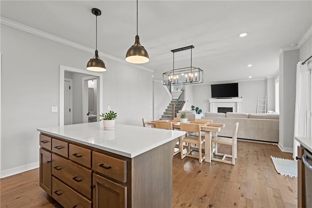 kitchen featuring crown molding, decorative light fixtures, light hardwood / wood-style flooring, and a center island