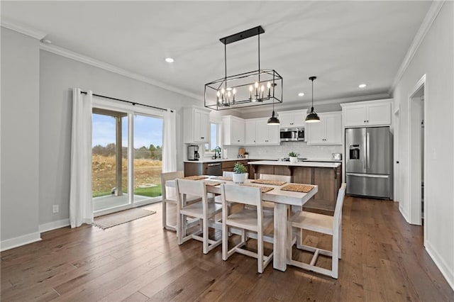 dining area featuring ornamental molding, wood-type flooring, and sink