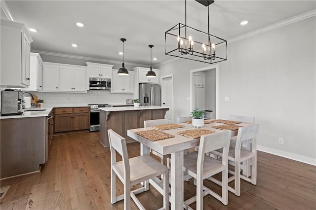 dining room featuring ornamental molding, sink, and dark hardwood / wood-style flooring